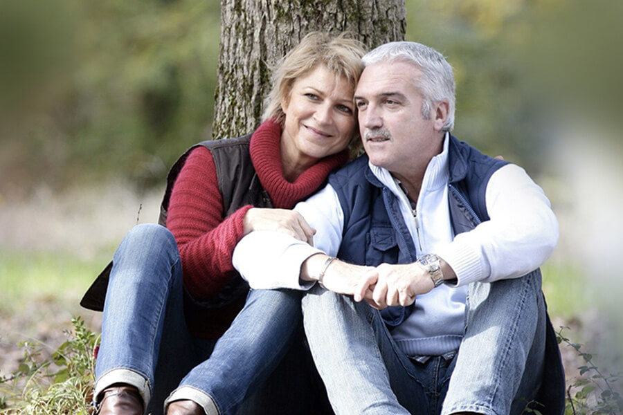 Older couple sitting by a tree